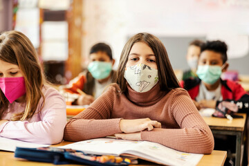 Portrait of a schoolgirl on a class with classmates during corona virus.