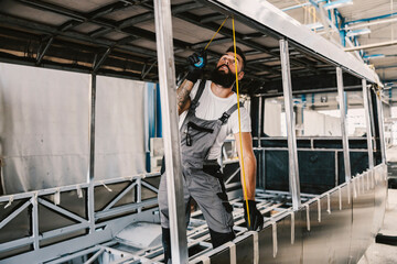 Fototapeta premium An auto mechanic measuring new bus at mechanic shop.