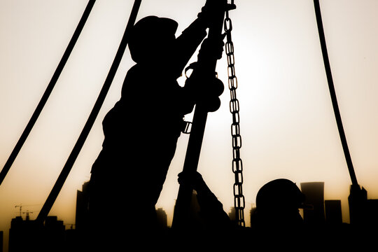 Doha,Qatar - December 11,2017. Construction workers preparing a crane for work in the background skyscrapers in Doha.