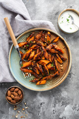 Honey garlic butter roasted carrots on a concrete background. Roasted carrots prepared with garlic butter and sweet honey sauce. Homemade glazed carrots