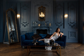 Obraz na płótnie Canvas Beautiful brunette in a silver dress posing in a classic interior