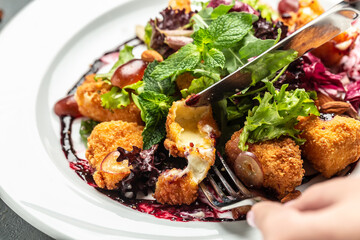 Salad Camembert cheese baked served on lettuce with vegetables, almonds and berry sauce. Food recipe background. Close up