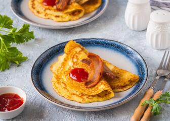 Swedish Ragmunk potato pancakes with fried bacon and berry sauce on a ceramic plate on a gray concrete background. Swedish cuisine.