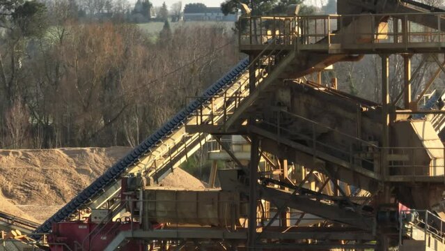 Aerial shot of machines and trucks working in a sand quarry, in France. Those are extracting and  filtering the sand.