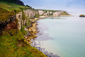 Coast near Carrick-a-Rede Rope Bridge, famous rope bridge near Ballintoy in County Antrim, Northern Ireland on Irish coastline. Wild Atlantic Way on cloudy day.