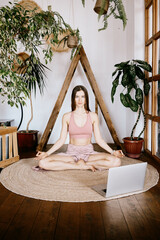 A woman taking yoga classes online at home.