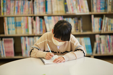 学校の図書館で宿題をしている可愛い子供の姿