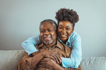 Close up faces of elderly 80s grandfather adult 30s granddaughter. Teenager girl sitting on window with father. Beautiful African American woman with her father as they both smile