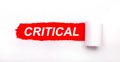 On a bright red background, white paper with a torn stripe and the inscription CRITICAL