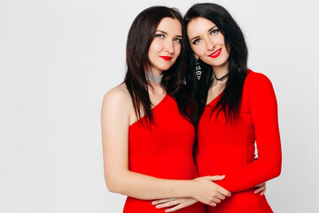 Two sexy sisters twins in red dresses.