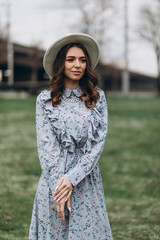 beautiful young woman in a hat and dress on the background of a field with flowers