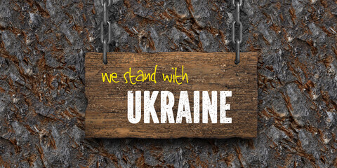 wooden sign with message WE STAND WITH UKRAINE on rocky background