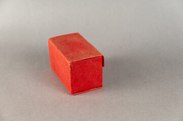 Closed red rectangular box on a gray background. Close-up. Selective focus.