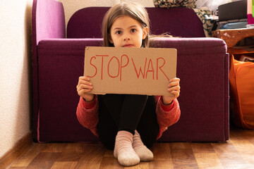 A little girl holds a poster with the words stop the war at her home in Ukraine and asks to stop the war in Ukraine, the children ask, a protest