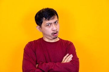 Obraz premium Asian man making angry expression on yellow background.