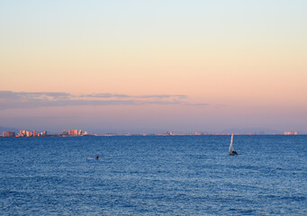 Sailboat at sea on sailing on the waves. Yachtsman during training on a sailboat. Skiff and Sailboat in sea port near the Spanish coast. Sail sport in Yacht club. Sail boat on waves on sunset in sea. 