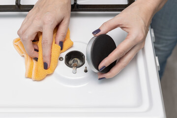 woman wipes the gas stove dismantling the burner