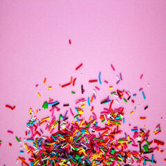Colorful sprinkles scattered on pink background