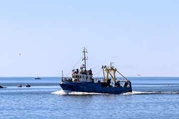 Fishing boat in the sea, seagulls fly