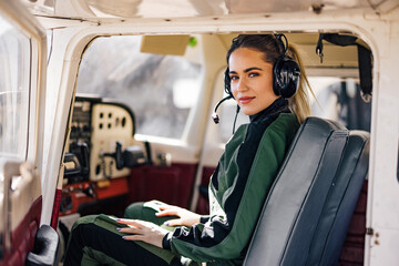 Portrait of the happy copilot, sitting in the cockpit, wearing aircraft headphones.