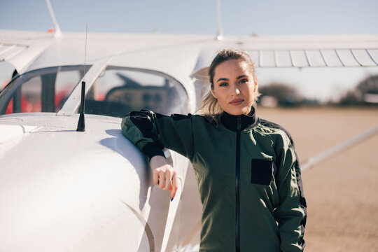 Portrait of a beautiful  female pilot, standing next to the plane.