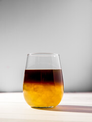iced or frozen bumble coffee in a glass, splash with drops, over grey background