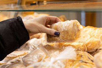 a girl with her hand takes out a pie from a showcase in a store