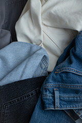 Denim trousers of different textures and colors stacked on top of each other