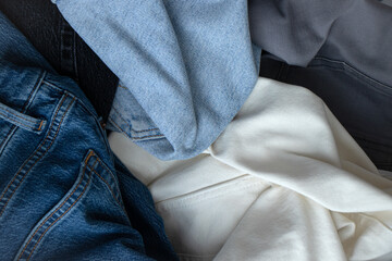 Denim trousers of different textures and colors stacked on top of each other