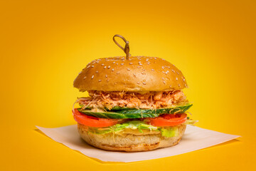 Juicy Burger with Crab Meat on a yellow background. Crab Meat, fresh Tomatoes and Cucumbers.
