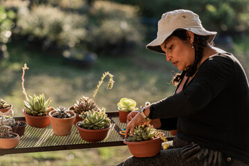 latina woman in sombrero sitting working with plants on a sunny day 