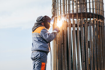 Workers is welding metal parts of concrete bridge