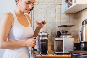 young woman in the kitchen preparing coffee with a manual french press coffee maker
