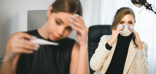 Young woman got sick in the office, high fever and virus symptoms. The colleague is unhappy and puts on a face mask. Coronavirus or flu