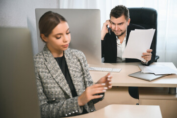 Obraz premium Young attractive woman and adult man are working in the office. Open space concept for teamwork