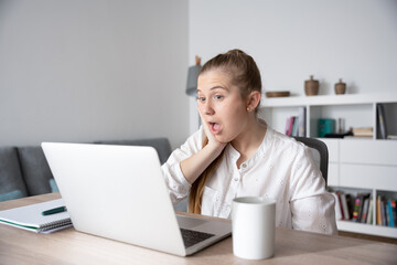 Surprised freelancer woman looking at laptop