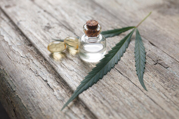 cannabis (hemp) essential oil bottle with cannabis leaves and seeds on wooden background