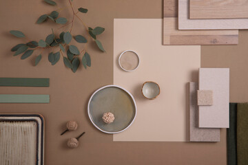 Creative flat lay composition of interior designer moodboard with textile and paint samples, panels and tiles. Beige, brown and green color palette. Copy space. Template.