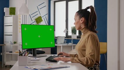 Business woman using computer with green screen in startup office. Company worker looking at...