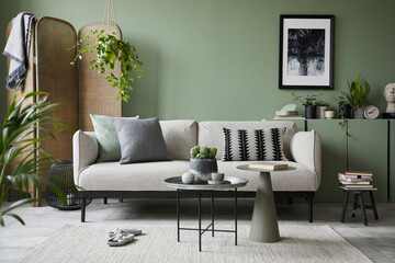 Stylish composition of modern living room interior. Mock up poster frame, modern sofa, folding screen, plants and personal accessories. Eucalyptus wall. Home staging. Template. Copy space.