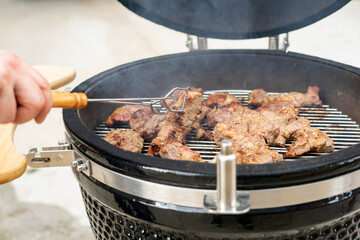 Steak on compact charcoal grill for travel in the cooking process.