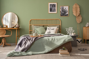 Stylish bedroom interior design with mock up poster frames, bed, side table, rattan commode, vanity table and creative home accessories. Sage green wall. Template. Copy space..