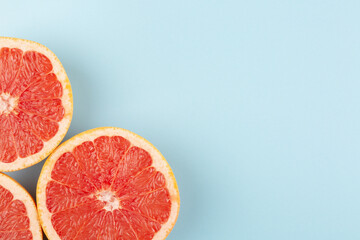 Sliced grapefruits on blue background, top view, flat lay	