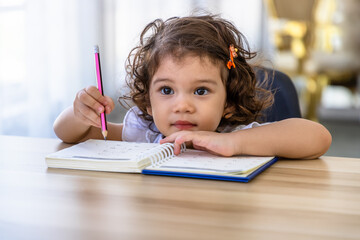 Cute young preschool Caucasian child girl drawing with pencil at desk