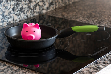 Concept of saving electricity consumption in a kitchen with a piggy bank