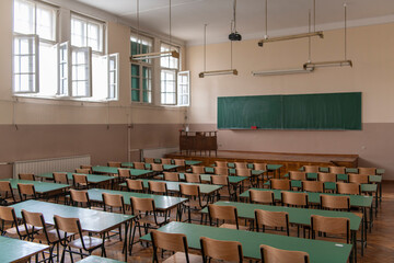 Empty old faculty or college School classroom with row of chairs, green desk tables, chalkboard and...