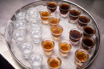 Lots of different kinds and colors of brandy cups (schnapps, rakija) on aluminium tray or plate.