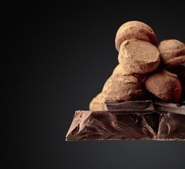 Large piece of dark chocolate and falling chocolate crumbs.