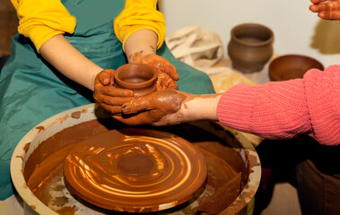 Master, teaches pottery. Hands of a potter making a crock on a circle