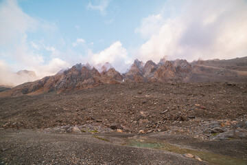 Scenic alpine landscape with rocky mountains in dense low clouds in morning sunlight. Colorful mountain scenery with sharp rocks among thick low clouds. Awesome view to high rockies in low cloudiness.